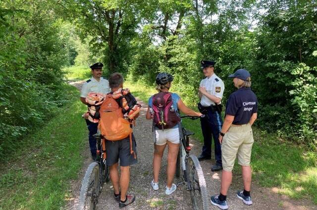 Zwei Beamte der Polizeiinspektion Traunstein mit einer Chiemsee Rangerin im Gespräch mit zwei Radfahrern Foto: Polizeiinspektion Traunstein